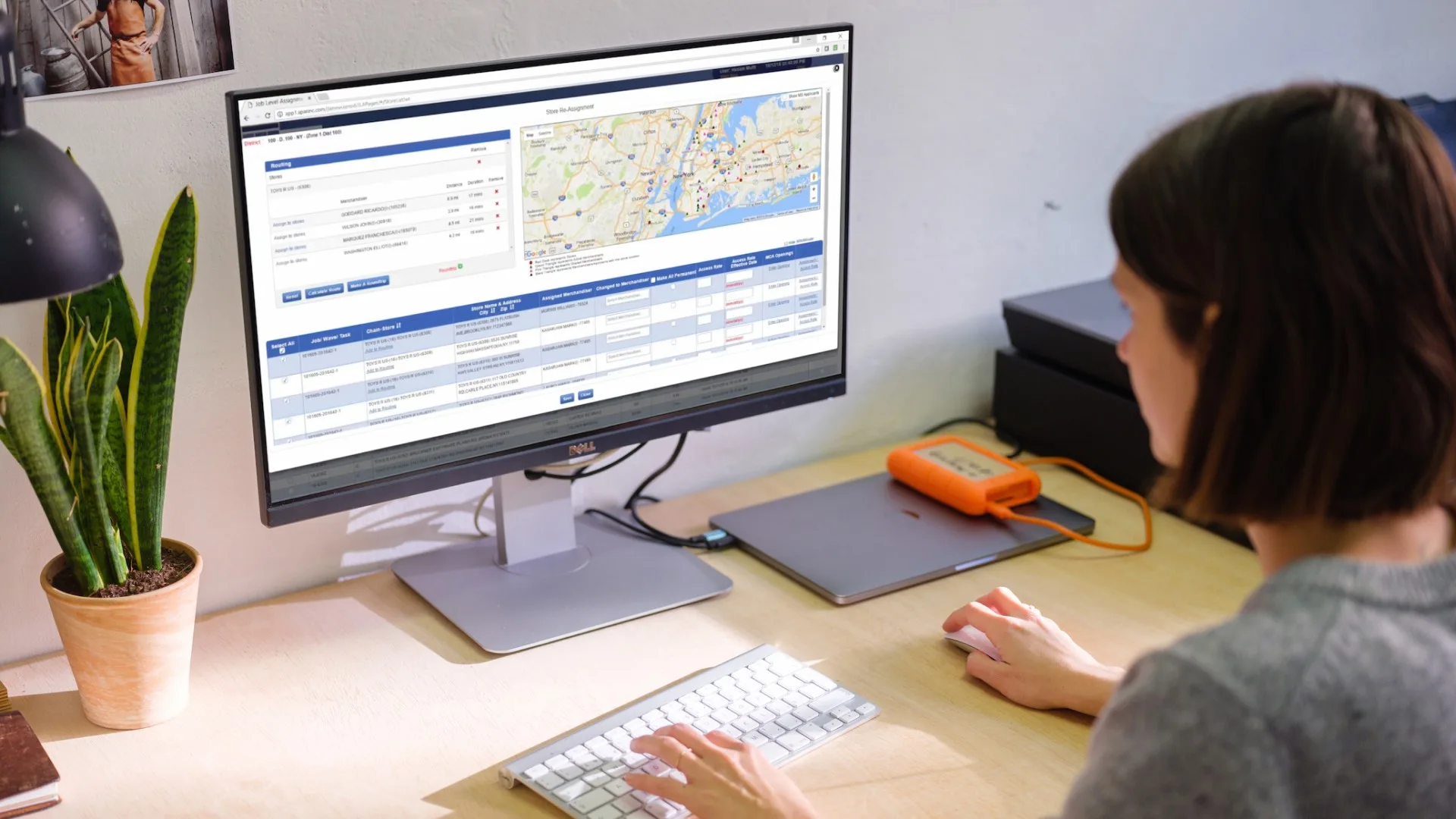A zone lead at a desk using SPAR’s Store Re-Assignment screen, with a routing panel, a map of store locations, and a table of jobs to reassign.